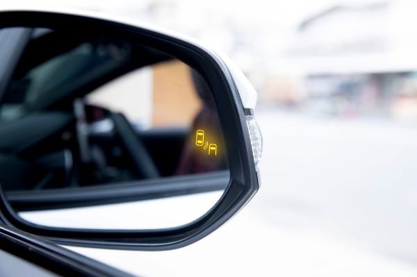 Blind spot monitor (BSM) warning light on car side mirror. Advanced driver assistance system