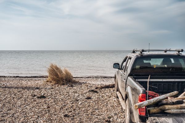 Beach landscape with a car under a blue sky. Cool car, pick up parked right on the beach.