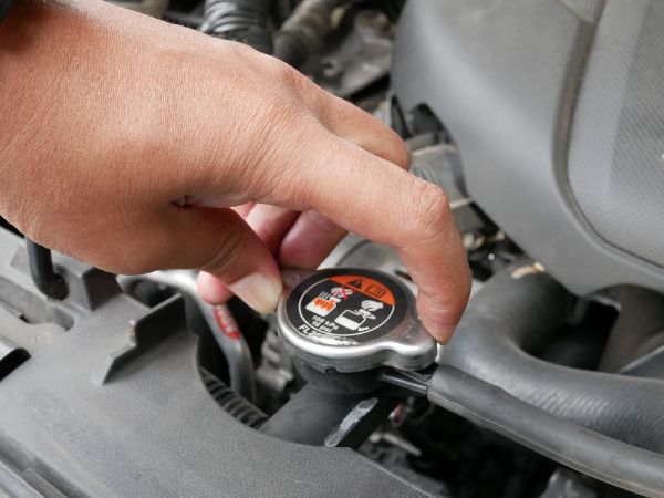 hand opening car radiator cap for engine cooling.