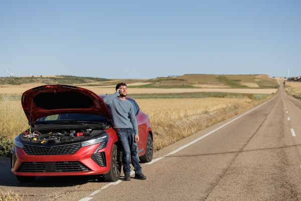 Displeased young adult man breaks down car in the middle of trip on the road calls tow truck to come