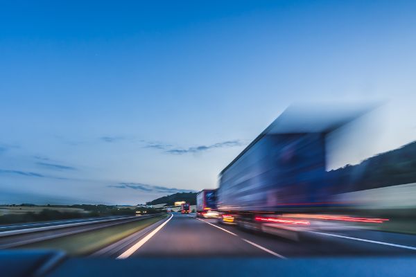 Background photograph of a highway, trucks on a highway, motion blur, light trails.