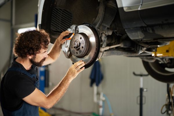 A mechanic inspects and repairs the brake system of a vehicle in a auto repair shop.
