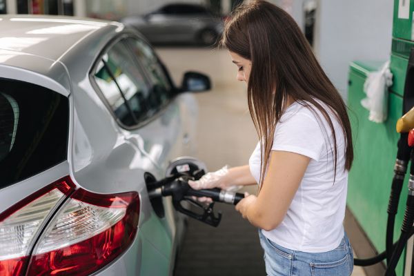 Female filling diesel at gasoline fuel in car using a fuel nozzle.