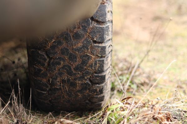 Pickup truck in mud, off-road tires, close-up. truck wheel on dirt road, dry grass.