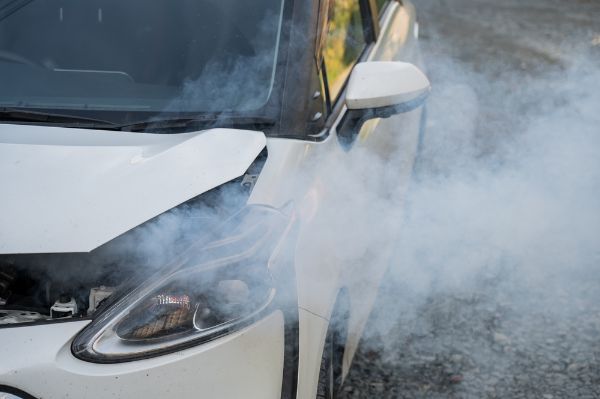 Smoke is coming from under the hood of the car