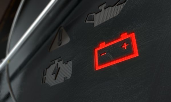 An extreme closeup of an illuminated check battery dashboard light on an dashboard panel