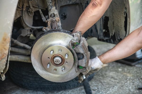 Mechanic man installing new brake disc and brake pads on car, car repair