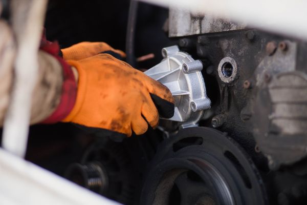 installation of a new water pump of the engine cooling system in a car service.