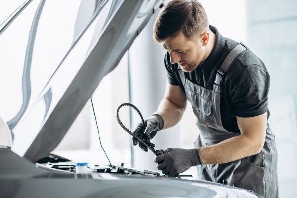 Car mechanic checking timing belt