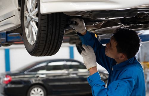 mechanic inspecting suspension of vehicle