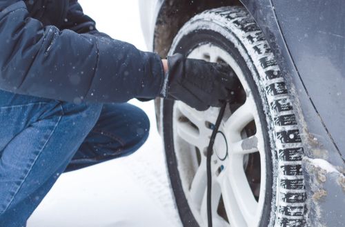 man filling tires with air in winter snow