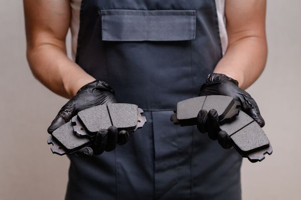 Auto mechanic holding four brake pads