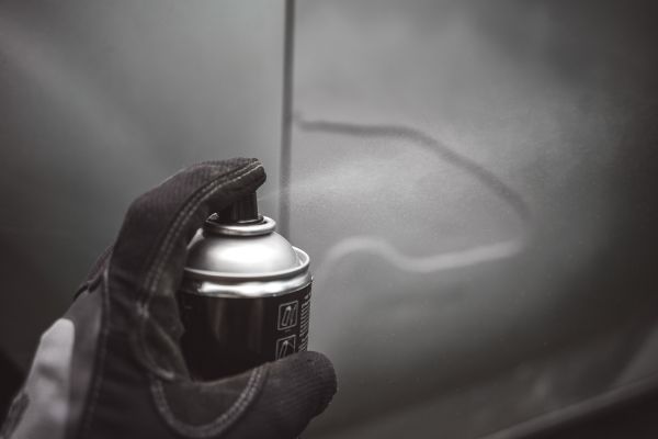 An Auto mechanic powder painting a vehicle