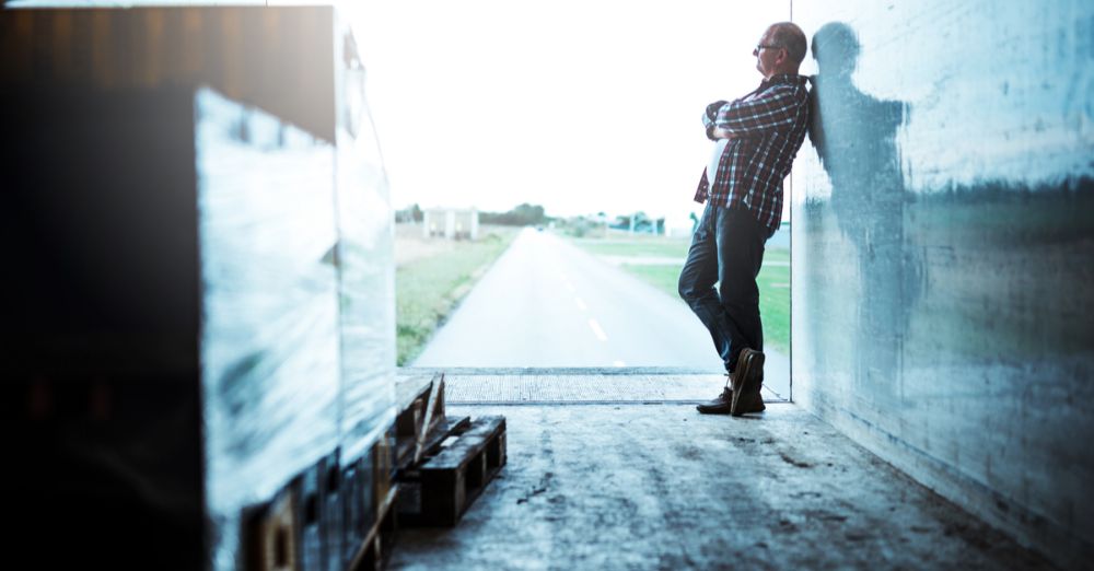 Man taking a break leaning against the wall in the back of a fleet truck in order to destress
