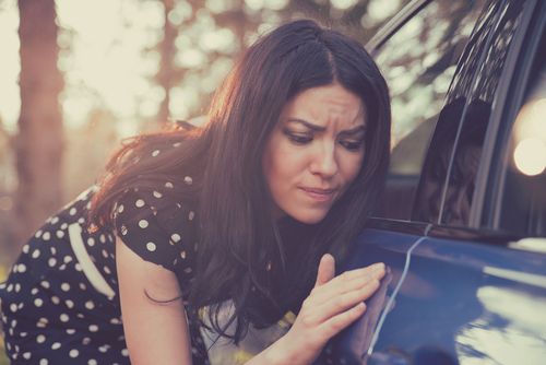 worried woman with scratch on vehicle