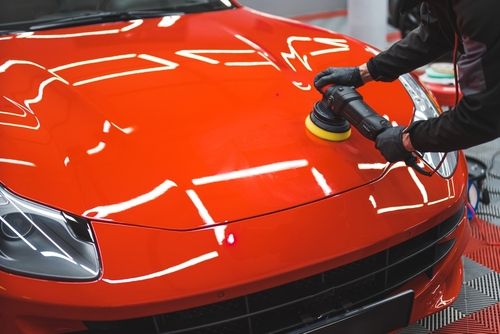 Auto body paint specialist buffering candy red sports car