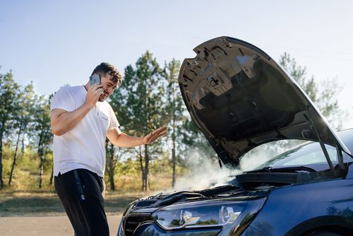 Man on phone with auto repair shop about overheated engine