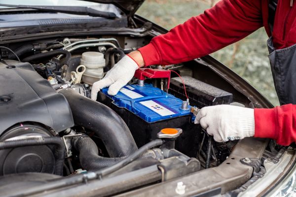 a car mechanic installs a battery in a car. Battery replacement and repair.