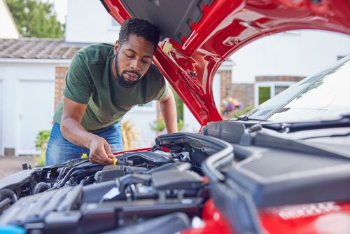 Man Working Under Hood Checking Car Engine Oil Level On Dipstick