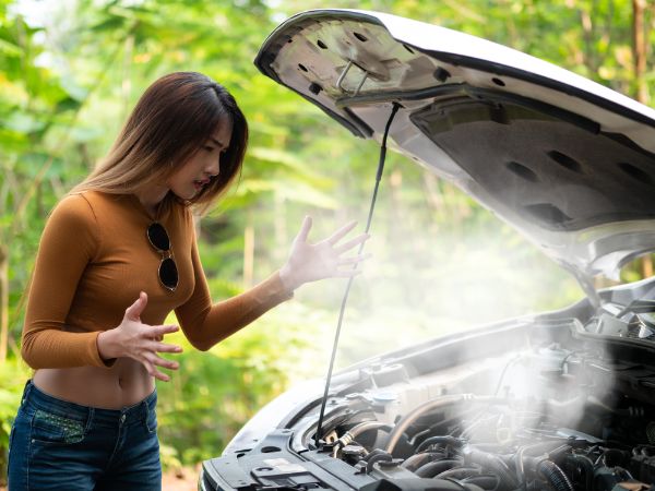 tourist looking at the Smoke out the radiator a car, Over Heat. parked at the side of the road.