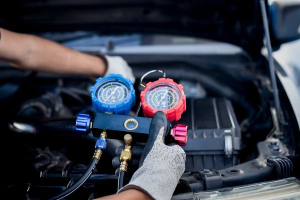 air conditioning technician, checks refrigerant and refills air conditioning on vehicle