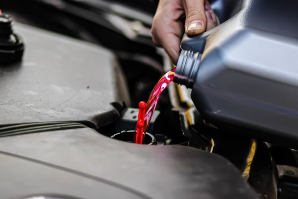 a mechanic pouring Antifreeze to a vehicle to prepare for the winter