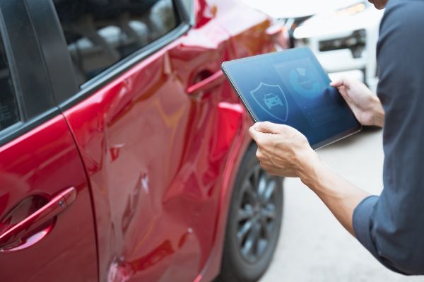an insurance agent from a collision shop inspecting collision damage for a customer's vehicle