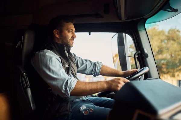 Side view of professional driver behind the wheel in truck's cabin