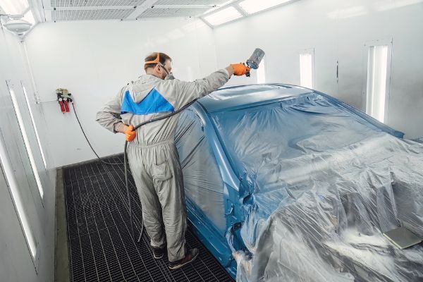 auto body technician painting vehicle