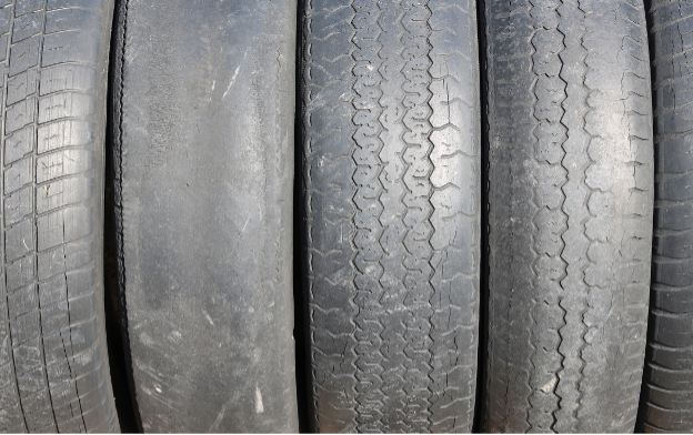 A row of tires are lined up with various degrees of wear.