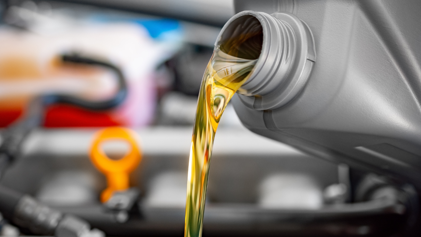 A close-up of golden colored car oil being poured.