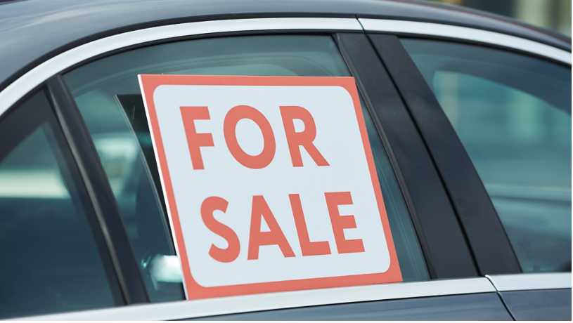 A car with a ”for sale” sign up in the back window.