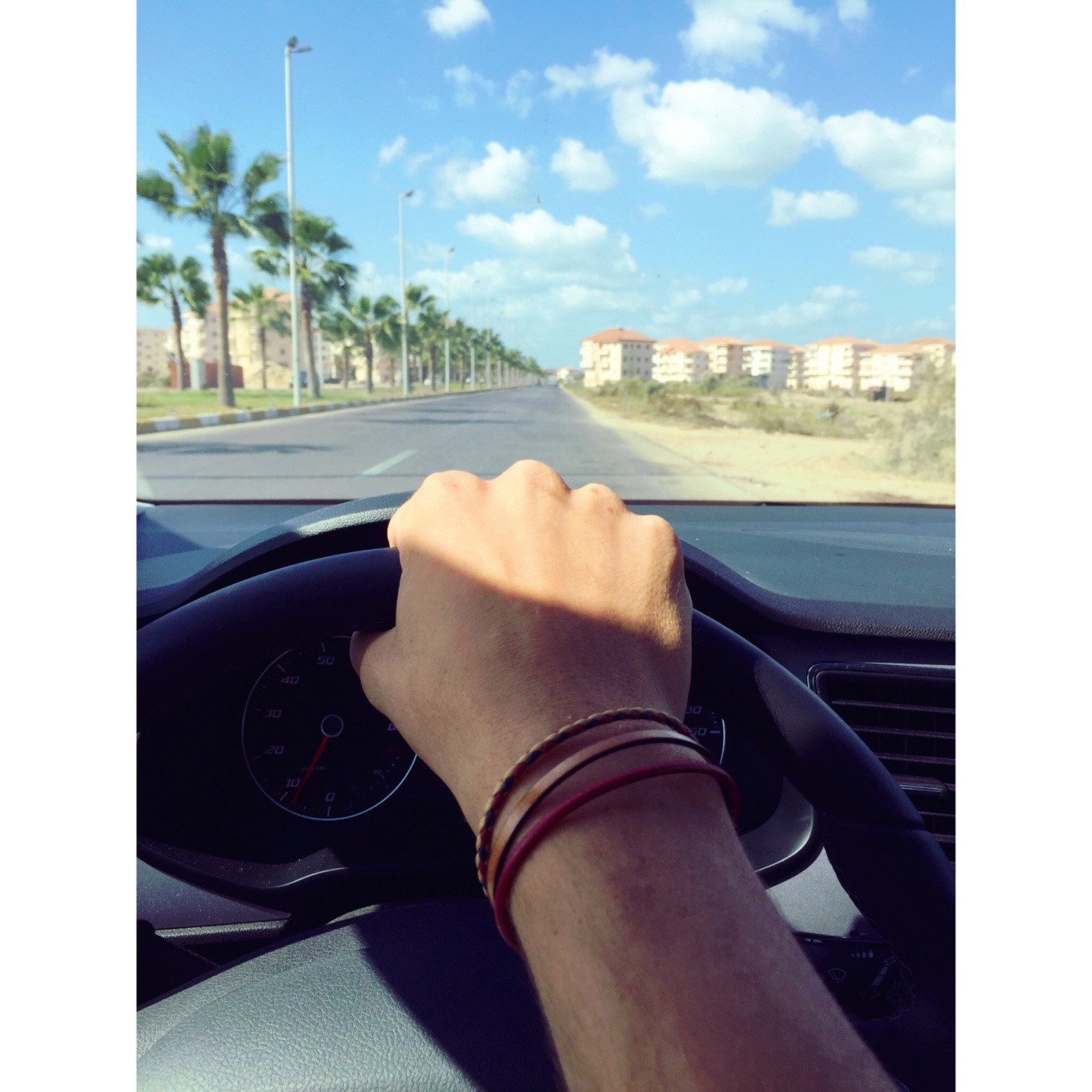 Hand on a steering wheel driving down to the beach