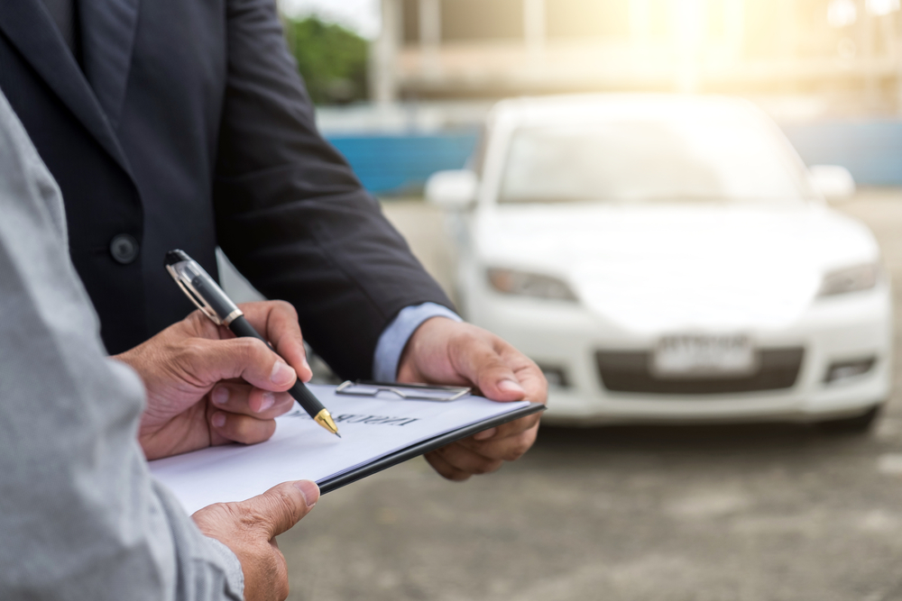 Insurance Agent examine Damaged Car and customer filing signature on Report Claim Form process